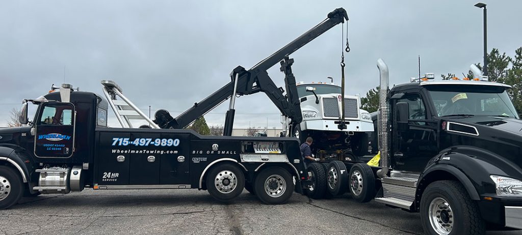 Wheelman Towing uses a heavy wrecker to lift a white semi‑truck for recovery.